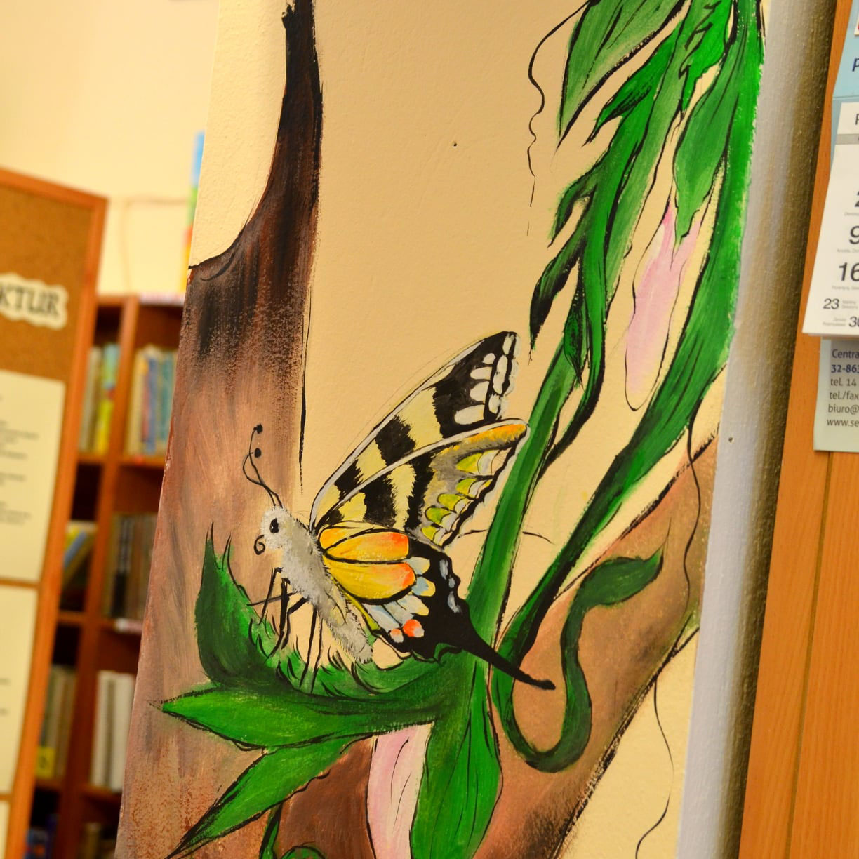 Kolejny fragment bibliotecznego muralu, półki z książkami w pastelowej tonacji